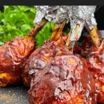 Smoked BBQ Chicken Lollipops with crispy skin and a sticky BBQ glaze served on a black plate.