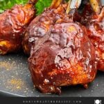 Smoked BBQ Chicken Lollipops with crispy skin and a sticky BBQ glaze served on a black plate.