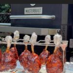 Finished smoked chicken lollipops hanging on the rack after being removed from the smoker.
