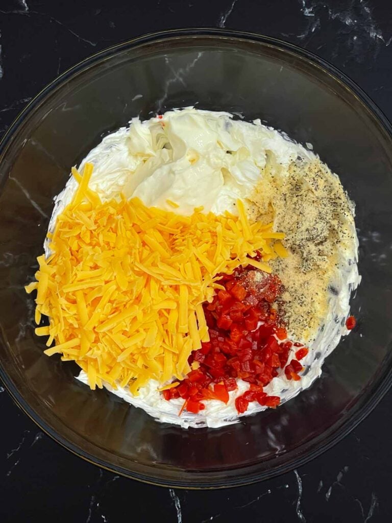 Cream cheese, sharp cheddar, mayonnaise, pimentos, garlic powder, onion powder, and black pepper in a mixing bowl.