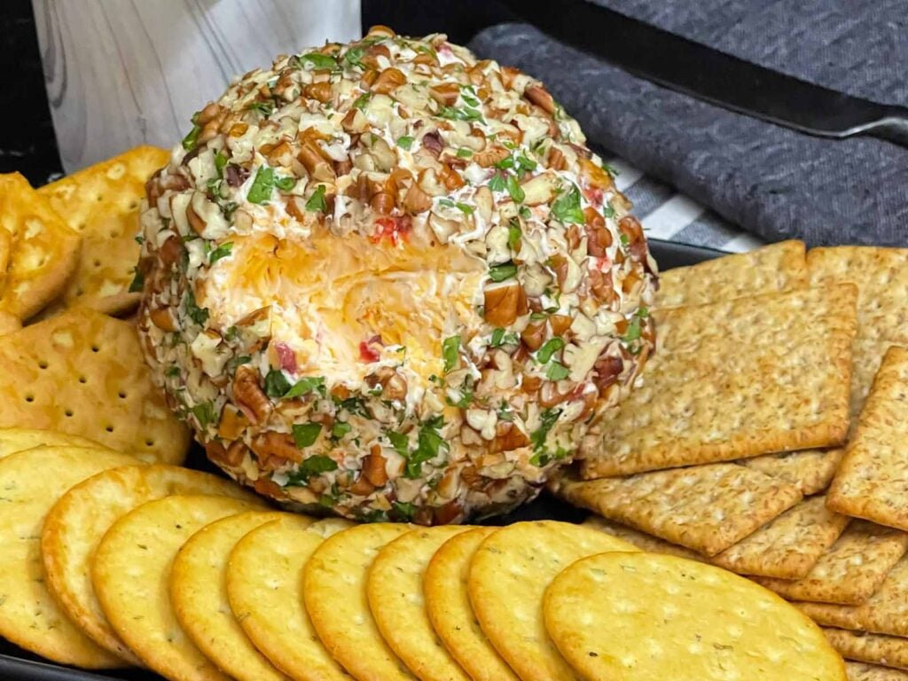 Creamy Pimento Cheese Ball with sharp cheddar and pimentos served with crackers.