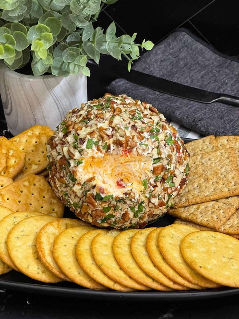 Pimento Cheese Ball coated in chopped pecans and served with crackers.