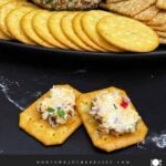 A scoop of creamy Pimento Cheese Ball on a cracker showing the cheesy pimento-filled center.