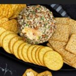 A scoop of creamy Pimento Cheese Ball on a cracker showing the cheesy pimento-filled center.