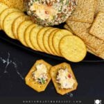 A scoop of creamy Pimento Cheese Ball on a cracker showing the cheesy pimento-filled center.