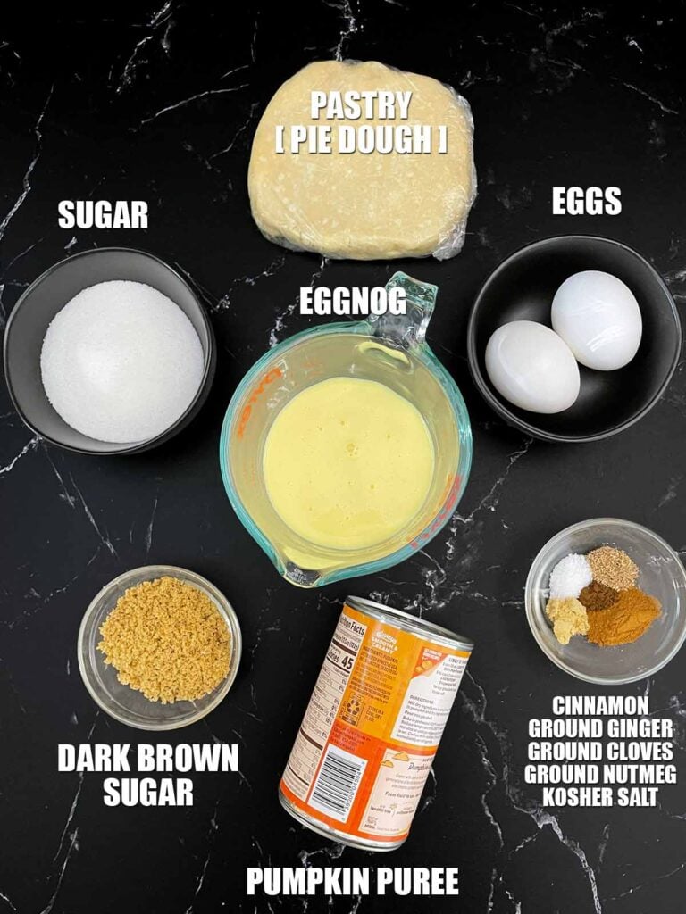 Ingredients for eggnog pumpkin pie, including pumpkin puree, eggnog, eggs, sugar, spices, and pie crust.