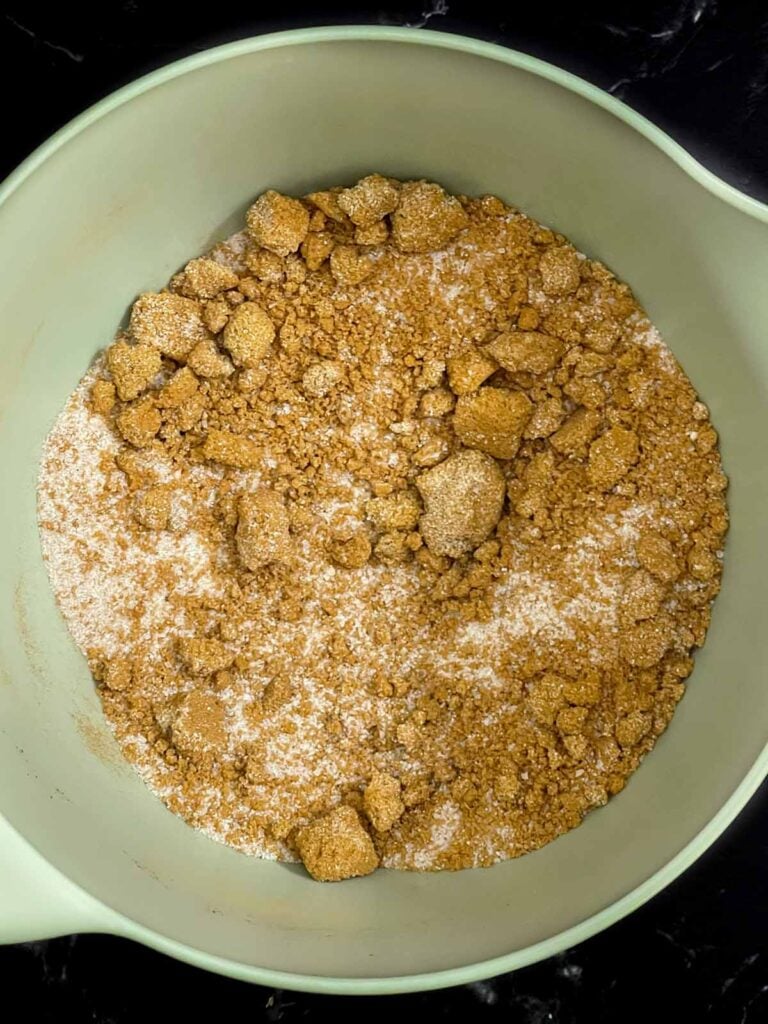 Granulated sugar, brown sugar, cinnamon, nutmeg, cloves, allspice, and salt mixed in a bowl for slow cooker apple butter.