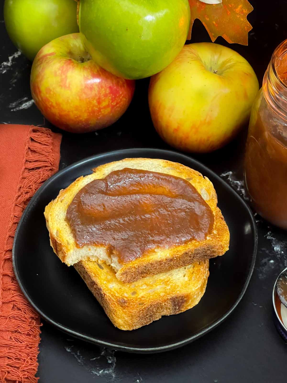 Slow cooker apple butter in a mason jar and smeared on a piece of sourdough toast.